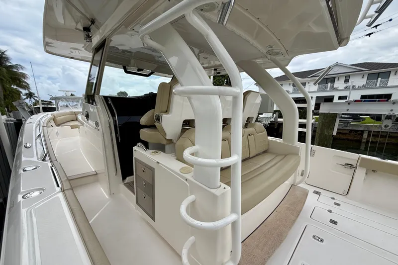 Slide: The Image of 2018 Pursuit S 408 Sport boat interior with seating and storage, docked near waterfront homes. - 46