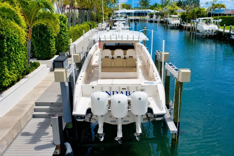 Slide: The Image of 2018 Pursuit S 408 Sport boat docked in a scenic marina with lush greenery. - 5