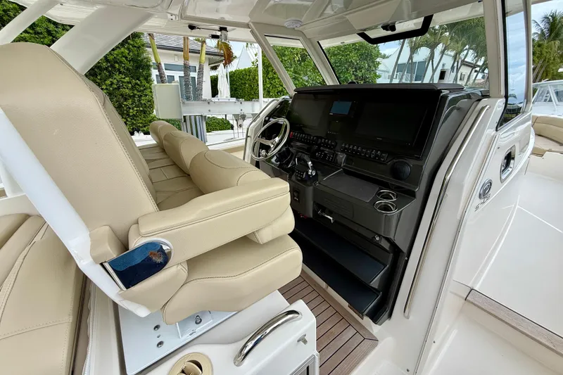 Slide: The Image of 2018 Pursuit S 408 Sport boat interior with beige seating and modern control panel. - 50