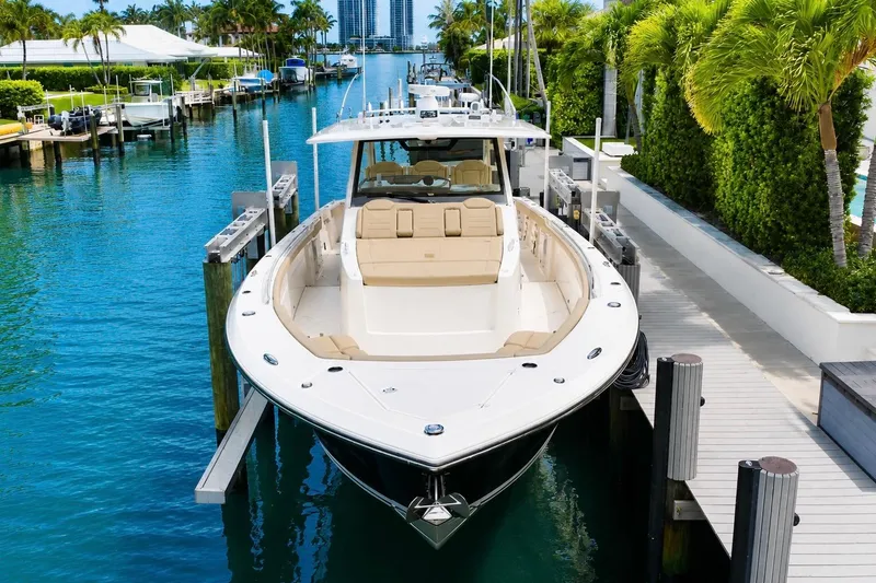Slide: The Image of 2018 Pursuit S 408 Sport boat docked in a scenic marina with lush greenery. - 6