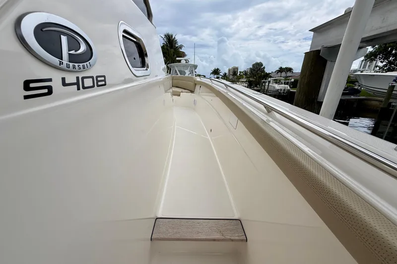 Slide: The Image of 2018 Pursuit S 408 Sport boat, side view with logo, docked near water. - 61