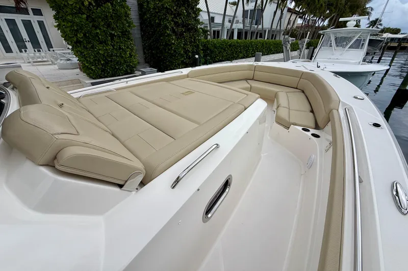 Slide: The Image of 2018 Pursuit S 408 Sport boat with beige seating, docked near lush greenery. - 62