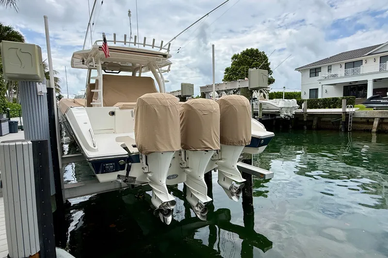 Slide: The Image of 2018 Pursuit S 408 Sport boat docked with covered engines, near waterfront property. - 8