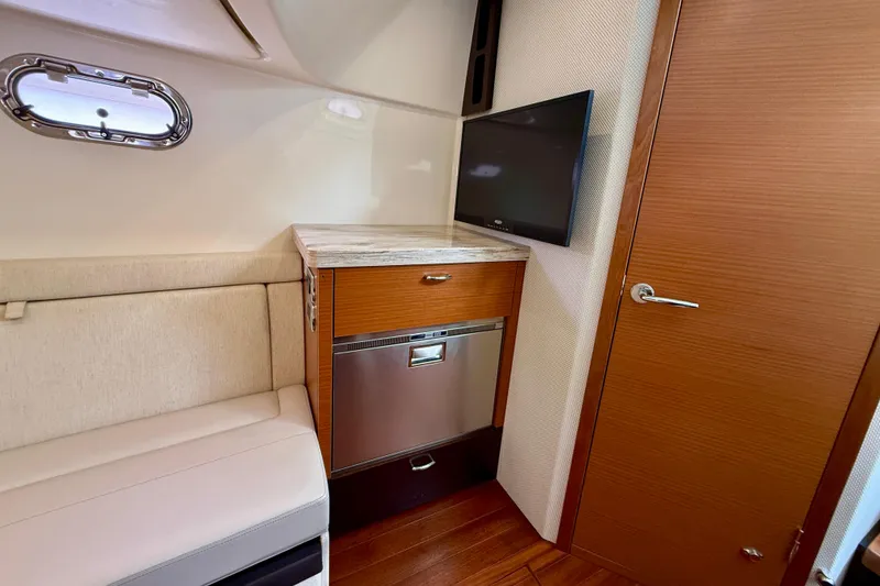 Slide: The Image of Interior of 2018 Pursuit S 408 Sport boat with seating, TV, and wooden cabinetry. - 82