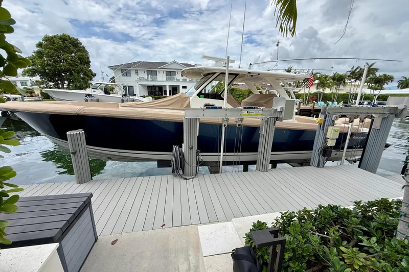 Slide: The Image of 2018 Pursuit S 408 Sport boat docked at a marina, surrounded by lush greenery. - 9