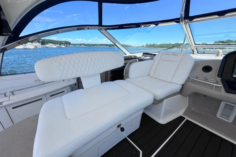 Slide: The Image of 2004 Sea Ray 500 Sundancer cockpit with white seating, overlooking a serene waterfront. - 18