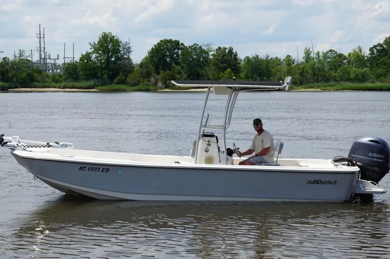 Slide: The Image of 2016 Sundance DX22 boat on calm river with Yamaha motor, piloted by a person. - 10