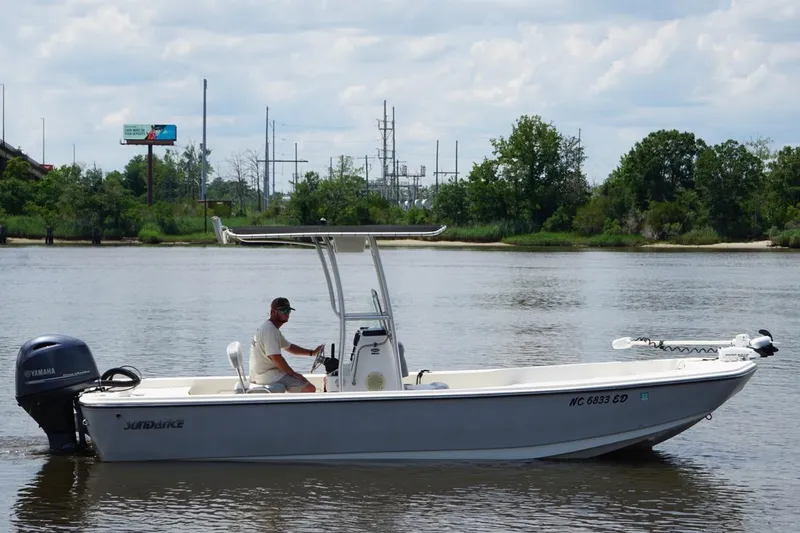 Slide: The Image of 2016 Sundance DX22 boat on a calm river with a Yamaha motor. - 6