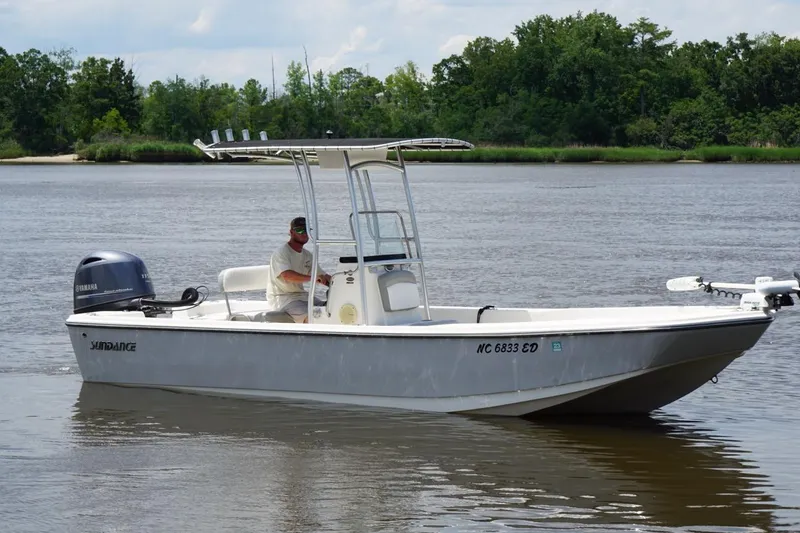 Slide: The Image of 2016 Sundance DX22 boat on a calm river with lush green shoreline. - 9