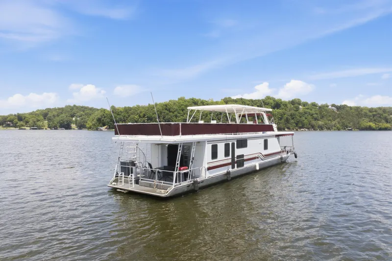 Slide: The Image of 2002 Sumerset 16x75 houseboat on a serene lake with lush green shoreline. - 7