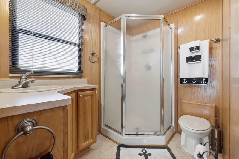 Slide: The Image of Bathroom in 2002 Sumerset 16x75 houseboat with shower, sink, and nautical-themed decor. - 84