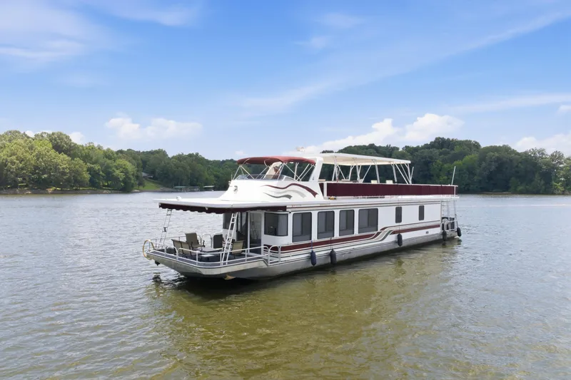 Slide: The Image of 2002 Sumerset 16x75 houseboat on a serene lake with lush green shoreline. - 5