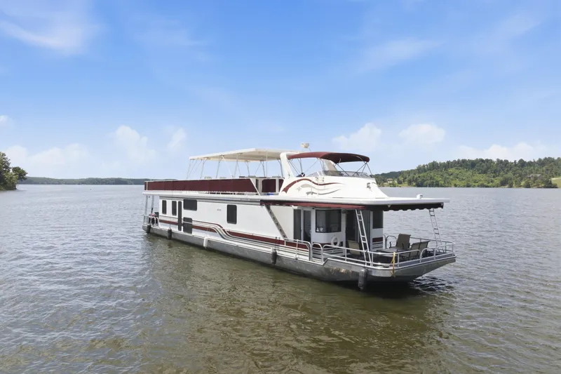 The Image of 2002 Sumerset 16x75 houseboat on a serene lake under a clear blue sky. - 0