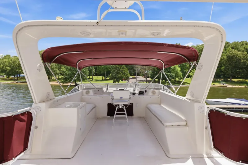 Slide: The Image of 2002 Sumerset 16x75 houseboat deck with maroon canopy, white seating, and scenic lake view. - 26