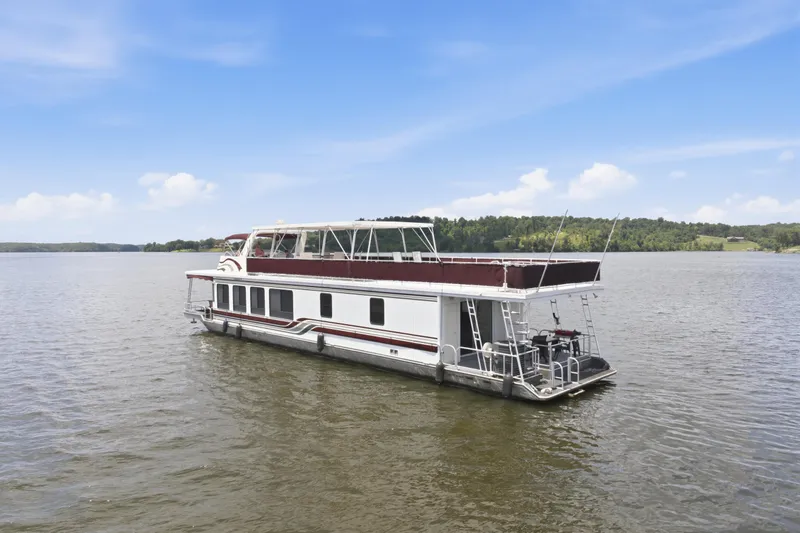 Slide: The Image of 2002 Sumerset 16x75 houseboat on a serene lake under a clear blue sky. - 1