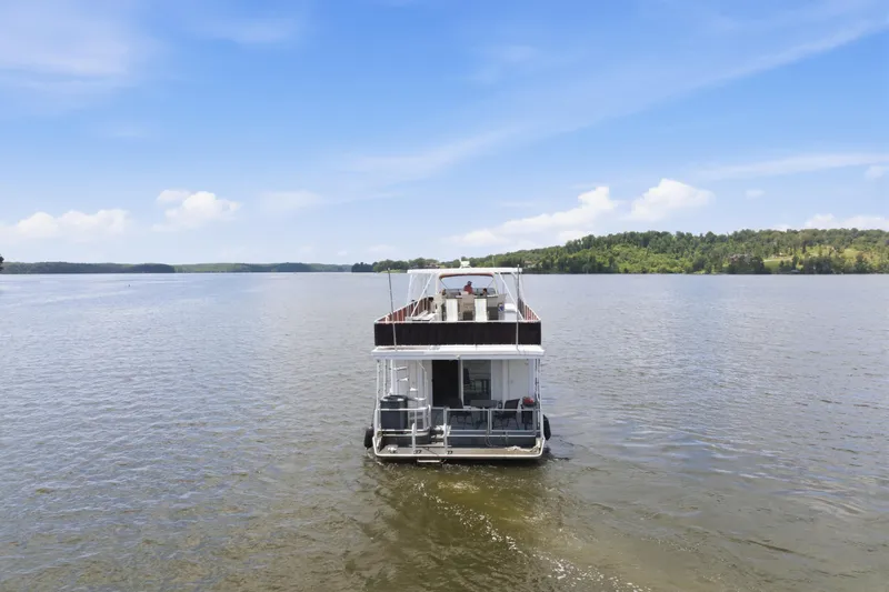 Slide: The Image of 2002 Sumerset 16x75 houseboat on a serene lake under a clear blue sky. - 3