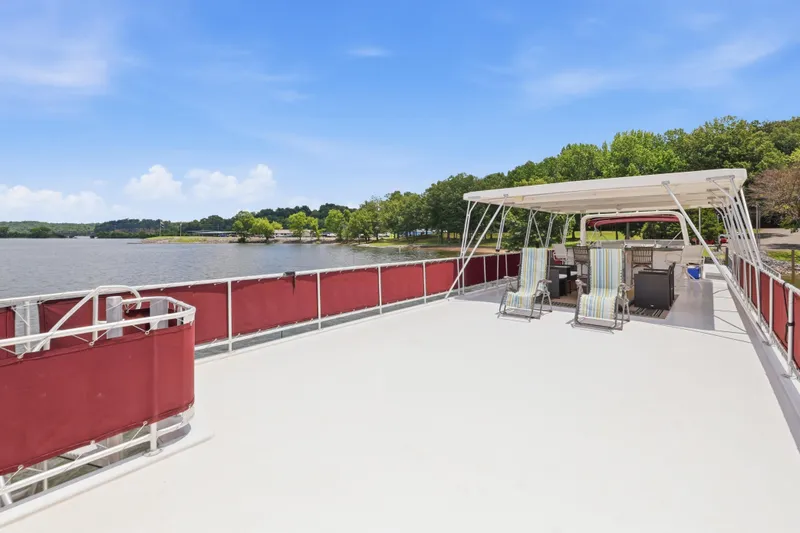 Slide: The Image of 2002 Sumerset 16x75 houseboat with spacious deck, lounge chairs, and scenic lake view. - 34