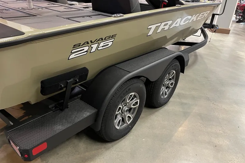 Slide: The Image of 2026 Tracker Savage 215 boat on a dual-axle trailer in showroom. - 3