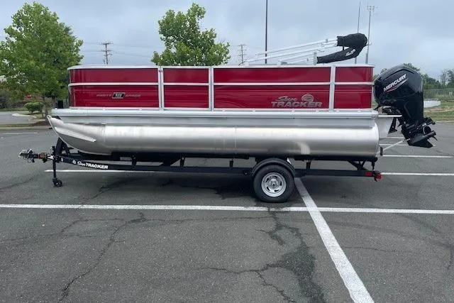Slide: The Image of 2026 Sun Tracker Party Barge 18 DLX pontoon boat on trailer in parking lot. - 23