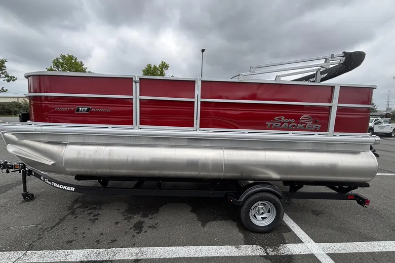 The Image of 2026 Sun Tracker Party Barge 18 DLX pontoon boat on trailer, parked outdoors. - 0