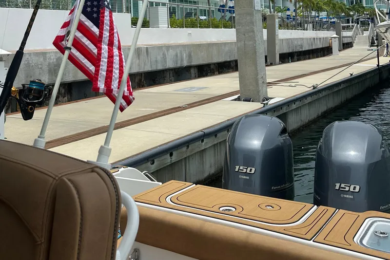 Slide: The Image of 2019 Sea Hunt Gamefish 25 with twin Yamaha 150 engines docked, featuring an American flag. - 14