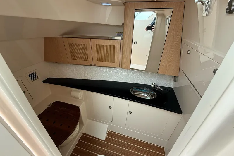 Slide: The Image of Interior of 2025 Grady-White Freedom 345 boat, featuring a modern bathroom with wood accents. - 30