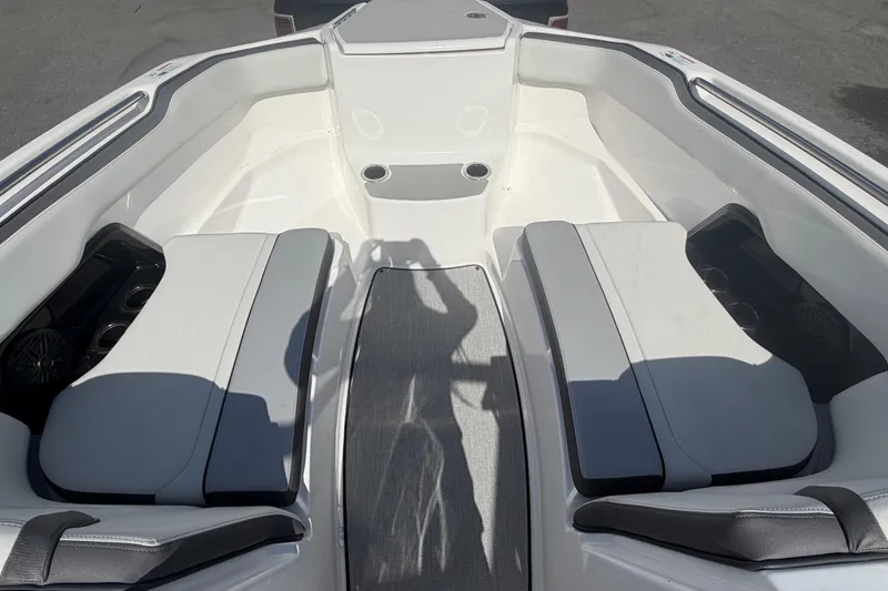 Slide: The Image of 2024 Yamaha Boats AR250 bow seating area with gray cushions and cup holders. - 17