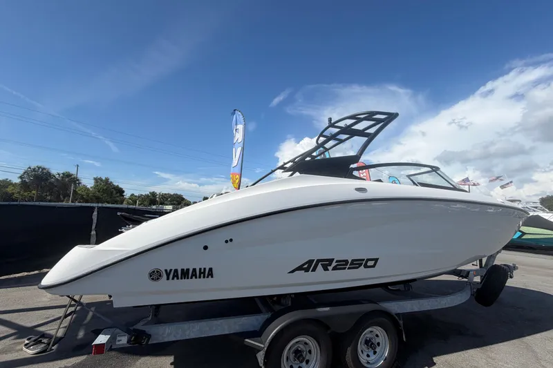 Slide: The Image of 2024 Yamaha AR250 boat on trailer under clear blue sky. - 2