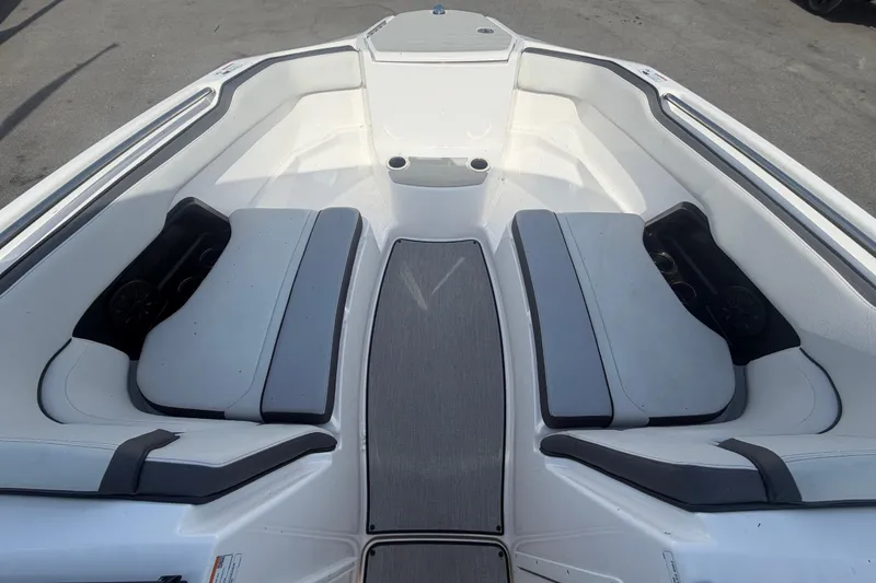 Slide: The Image of 2025 Yamaha Boats AR250 bow seating area with gray cushions and cup holders. - 35