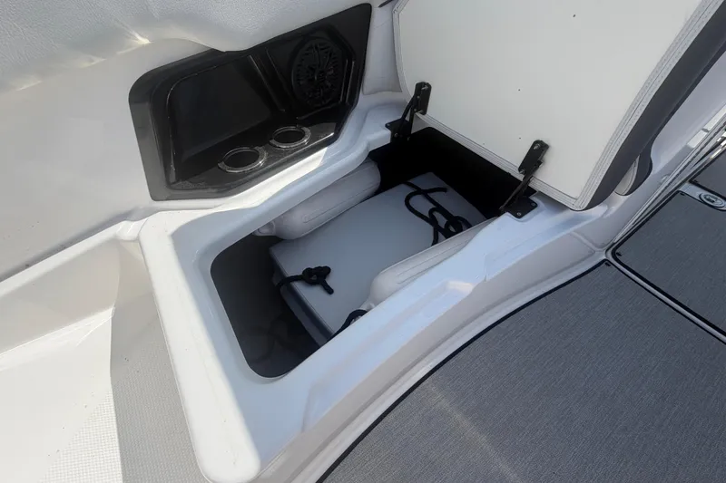Slide: The Image of 2025 Yamaha Boats AR250 storage compartment with cup holders and speaker. - 38