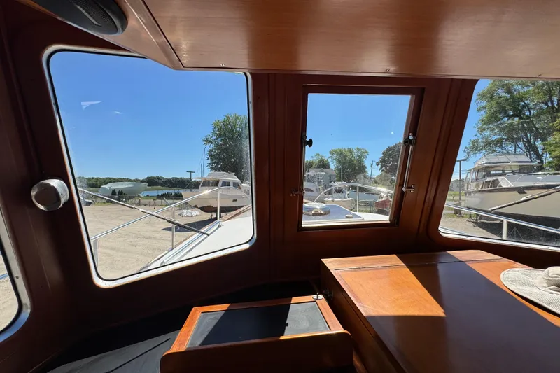 Slide: The Image of Interior view of 1998 Pacific Seacraft Pilothouse 32, showcasing wooden cabin and marina scenery. - 23