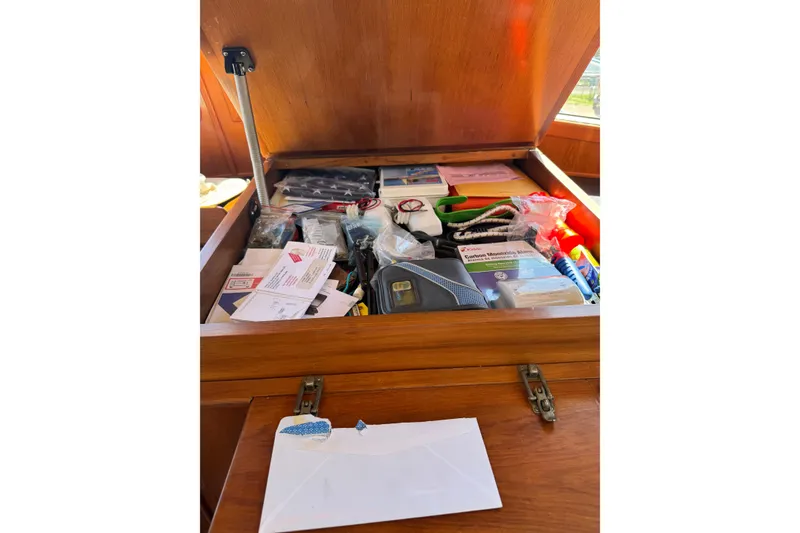 Slide: The Image of Storage compartment in a 1998 Pacific Seacraft Pilothouse 32, filled with various items and documents. - 30