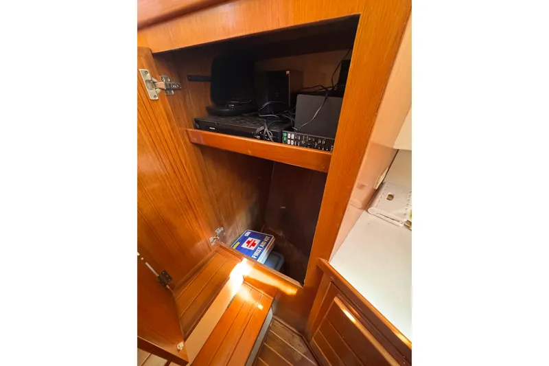 Slide: The Image of Wooden cabinet interior on 1998 Pacific Seacraft Pilothouse 32, featuring electronics and storage. - 38