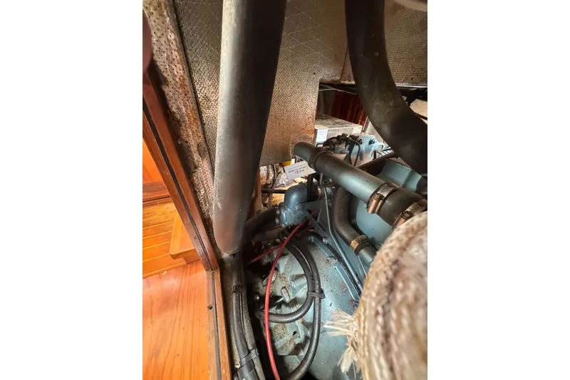 Slide: The Image of Engine compartment of 1998 Transpacific Marine Pilothouse 32, showcasing mechanical components and hoses. - 48