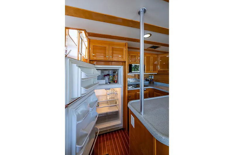 Slide: The Image of Galley kitchen in 2003 Magna Marine Nova Scotia 47 yacht with open fridge and wooden cabinetry. - 11