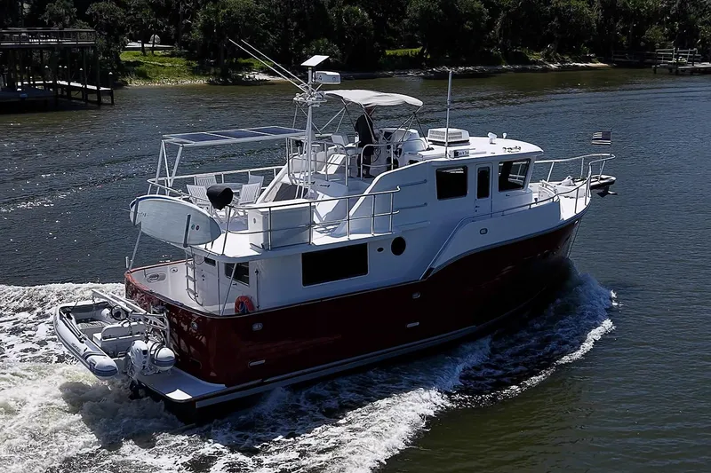 Slide: The Image of 2003 Magna Marine Nova Scotia 47 yacht cruising on a river, showcasing sleek design and spacious deck. - 2