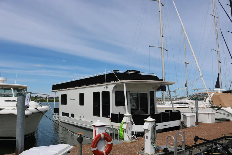 Slide: The Image of 2010 Skipperliner 480 Flybridge docked at marina, surrounded by sailboats under a clear sky. - 1