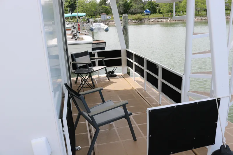 Slide: The Image of Skipperliner 480 Flybridge 2010 boat deck with chairs overlooking serene water. - 11