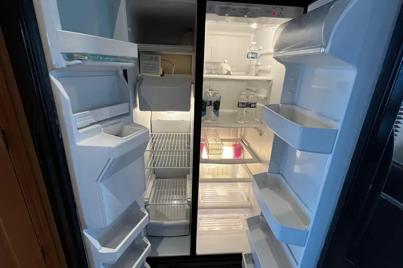 Slide: The Image of Open refrigerator on Skipperliner 480 Flybridge, showing shelves with bottled water and minimal items. - 28