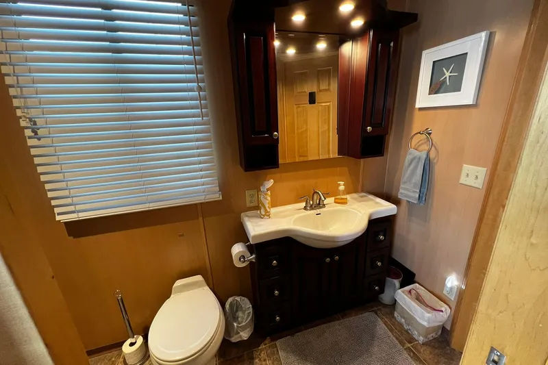 Slide: The Image of Bathroom interior of 2010 Skipperliner 480 Flybridge with sink, toilet, and wooden cabinetry. - 36