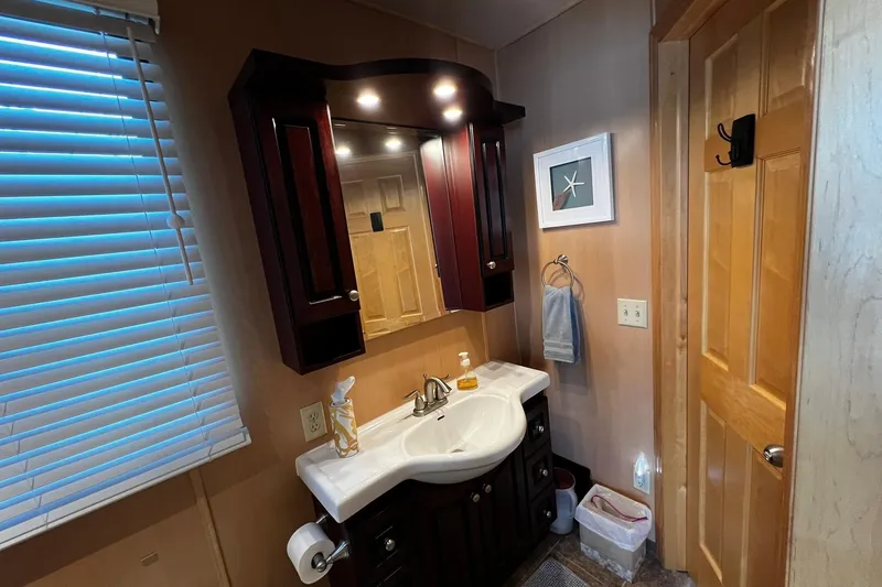 Slide: The Image of Bathroom vanity area on a 2010 Skipperliner 480 Flybridge with wooden cabinets and mirror. - 37