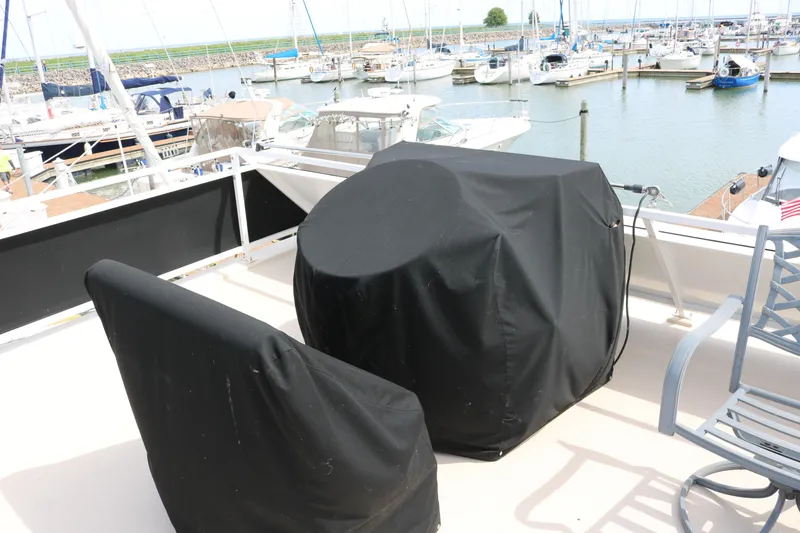 Slide: The Image of Flybridge of 2010 Skipperliner 480, covered furniture, overlooking marina with docked boats. - 45
