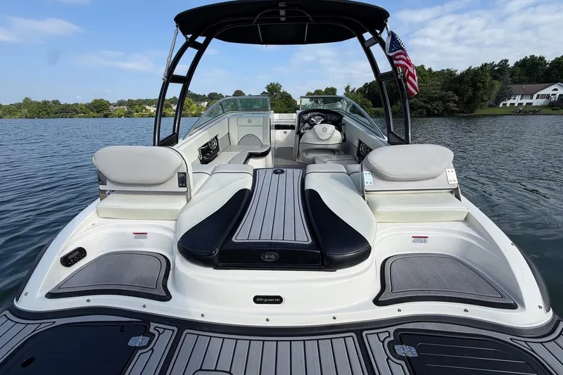 Slide: The Image of 2013 Bryant 210 Walkabout boat on a lake, featuring sleek seating and American flag. - 14