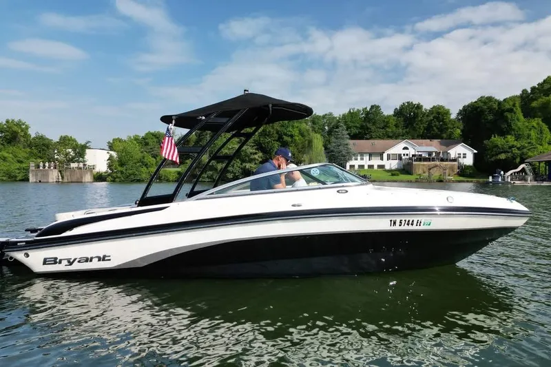 The Image of 2013 Bryant 210 Walkabout boat cruising on a scenic lake with lush greenery. - 0
