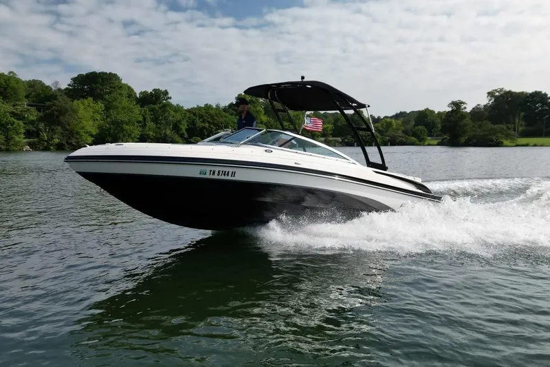 Slide: The Image of 2013 Bryant 210 Walkabout boat cruising on a lake with lush green surroundings. - 7