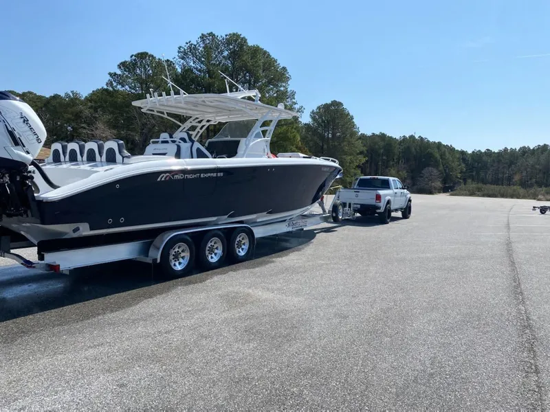 Slide: The Image of 2019 Midnight Express 39 Cuddy boat on trailer, towed by a truck in a parking area. - 23