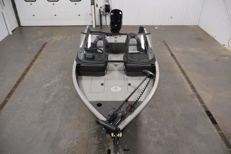 Slide: The Image of 2026 Crestliner 1650 Hawk WT fishing boat in a garage, featuring dual consoles and trolling motor. - 17