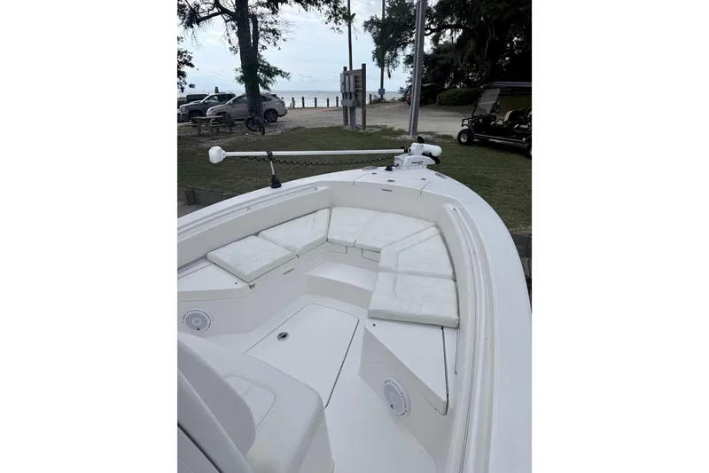 Slide: The Image of 2020 Regulator 24XO boat with cushioned seating and trolling motor, parked near a beach. - 2