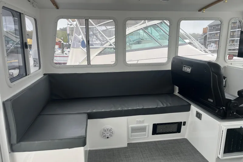 Slide: The Image of Interior of 2018 H&H Marine Osmond Beal boat with cushioned seating and large windows. - 44