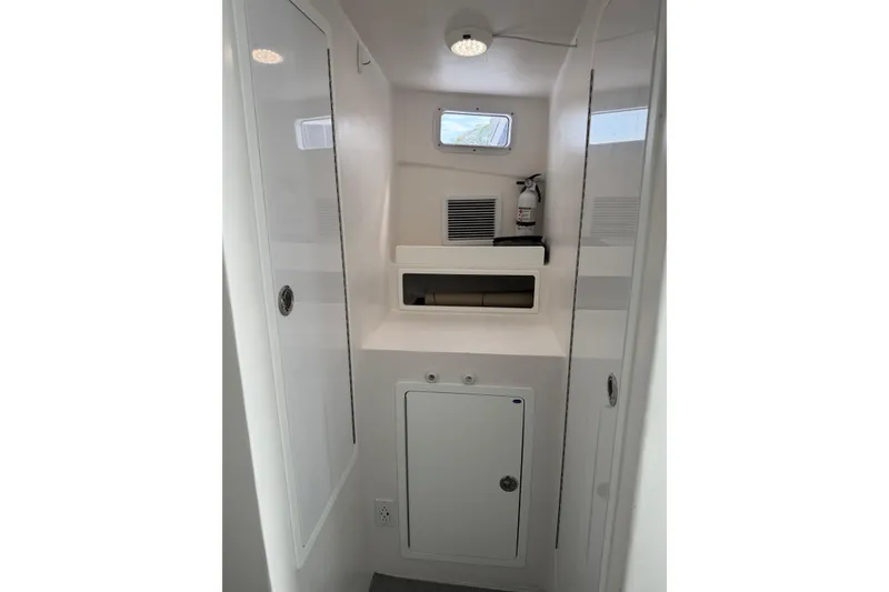 Slide: The Image of Interior of 2018 H&H Marine Osmond Beal boat, featuring storage compartments and a fire extinguisher. - 51